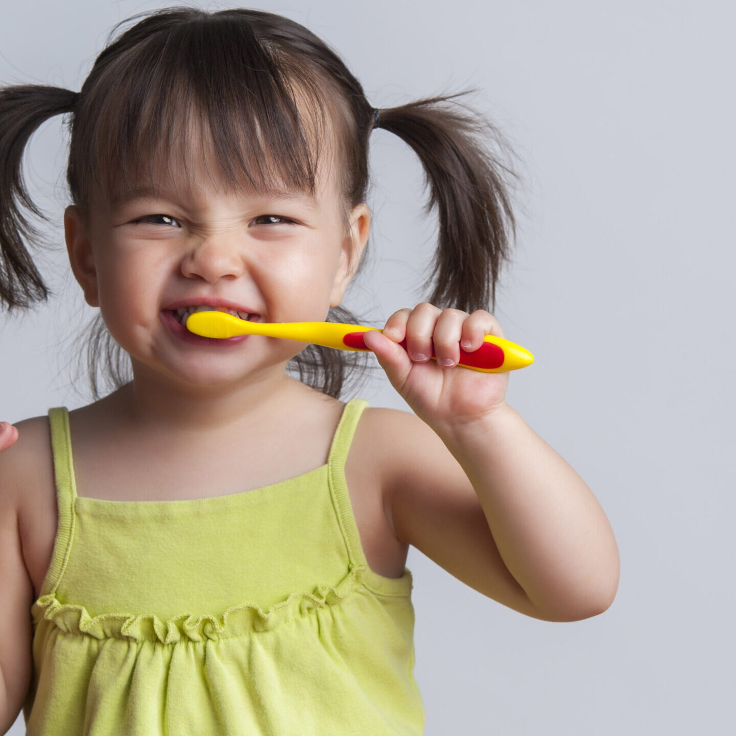 Toddler smiling while brushing her teeth